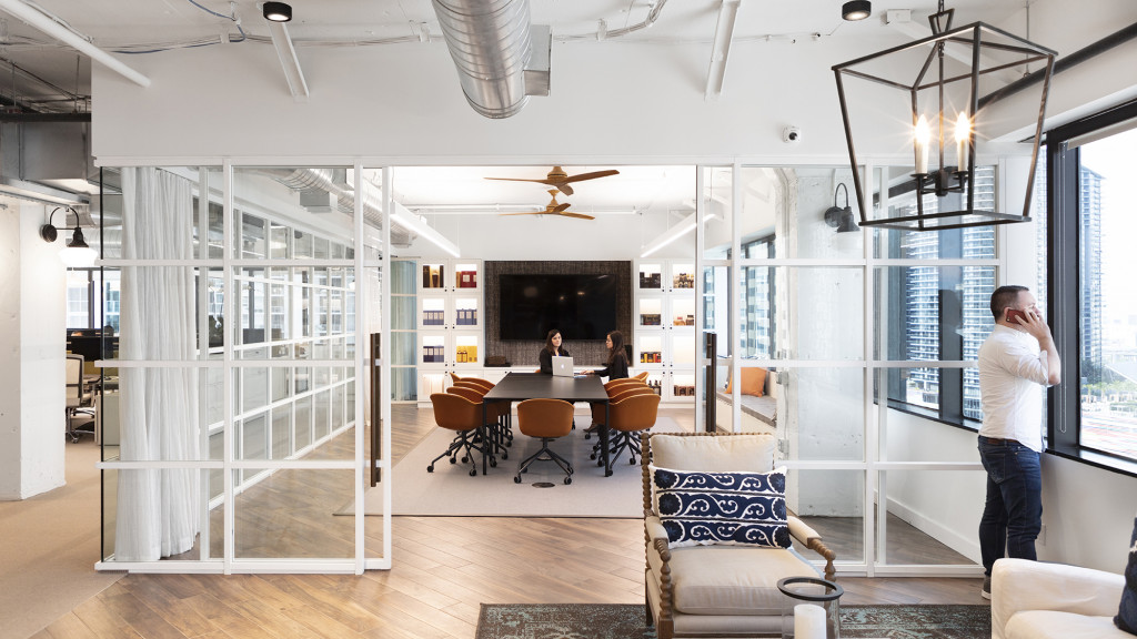 A person standing in a room with a table and chairs.